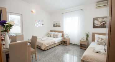 Triple studio apartment with a sea view, double and single bed, and nightstands in Villa Kovacevic
